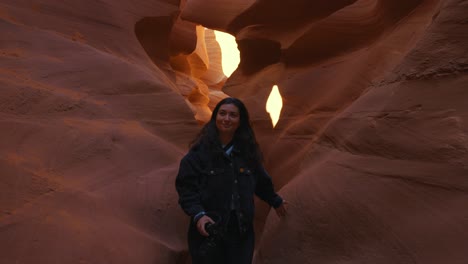 young woman walking at antelope canyon, arizona, smooth wavy sandstone walls