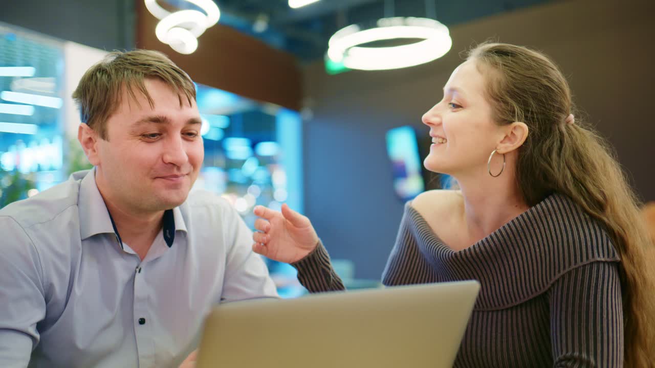 Forretningskolleger diskuterer idéer på laptop på moderne café