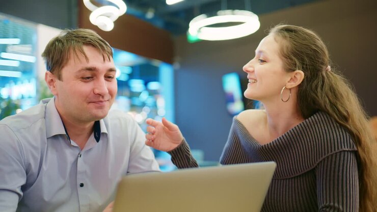 Forretningskolleger diskuterer idéer på laptop på moderne café