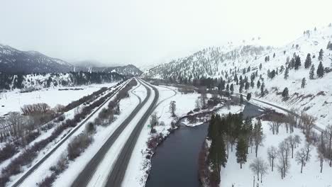 aerial - rural highway follows cold river during snowstorm