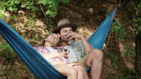 una pareja enamorada relajándose en una hamaca en el bosque