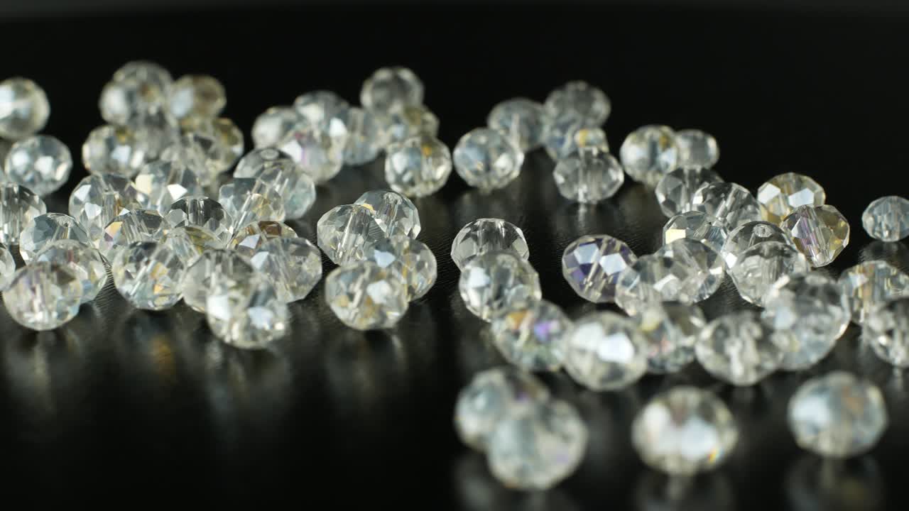 흑색 표면에 보석을 만들고 회전하기위한 색 구슬: 보석을위한 이리데센트 돌의 4k 비디오 클로즈업.