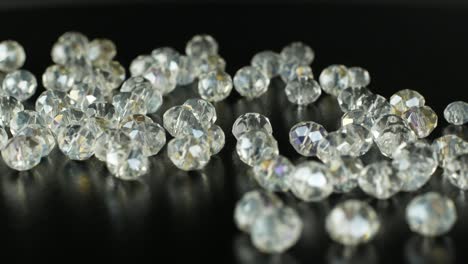 white beads for making jewelry on a black surface and rotating. 4k video close-up of iridescent stones for jewelry.