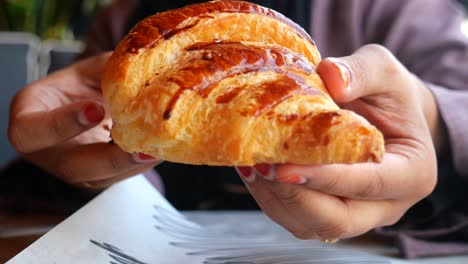 a person holds a freshly baked croissant with chocolate drizzle