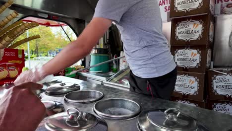 witness the dexterity and showmanship of a turkish gelato vendor in konya as they skillfully scoop, twirl and serve ice cream, delighting passers-by with their friendly and entertaining antics
