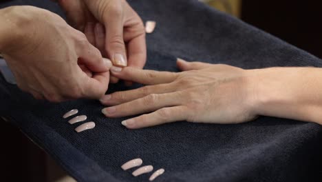 a close-up of a skilled nail technician meticulously working on natural color nail tips for a female client