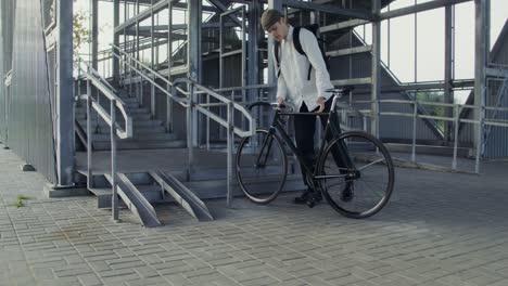 man carrying bicycle up stairs at an industrial structure