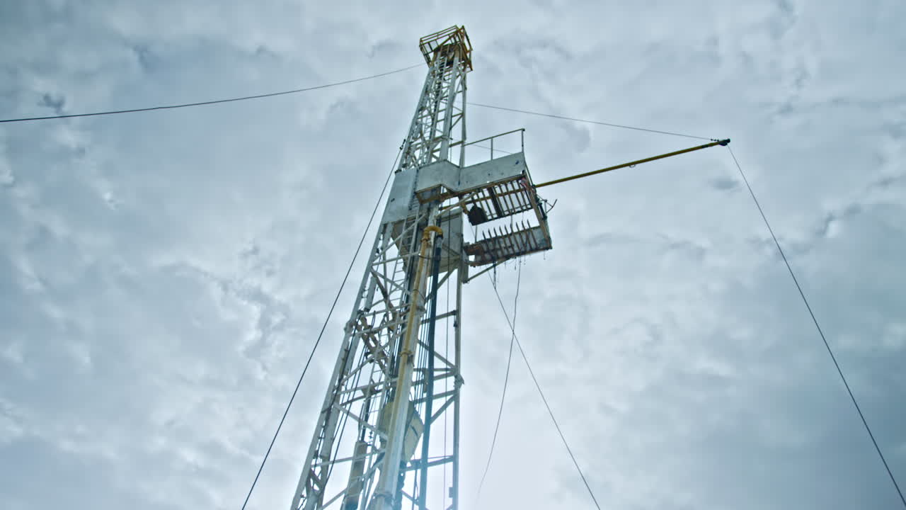 Cabin for work staff at the site for gas or oil production. Rig tower for drilling is at backdrop. Low angle view.