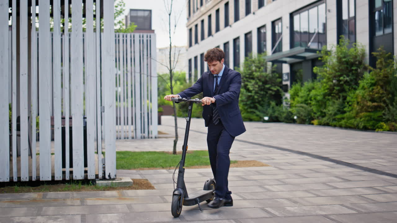 Businessman taking electric scooter in modern urban area. Elegant man riding
