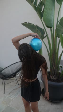 young woman playing with a blue balloon