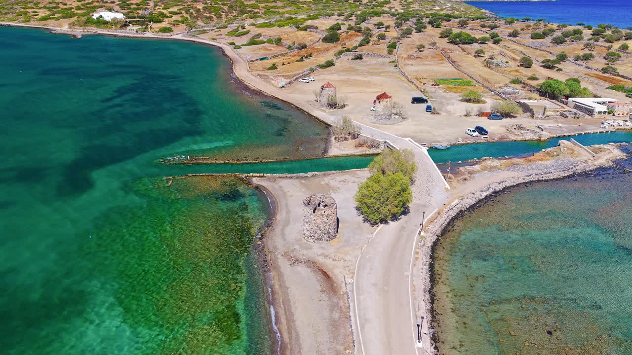 Aerial orbit of a causeway with old windmills and a canal at Elounda, Crete, Greece