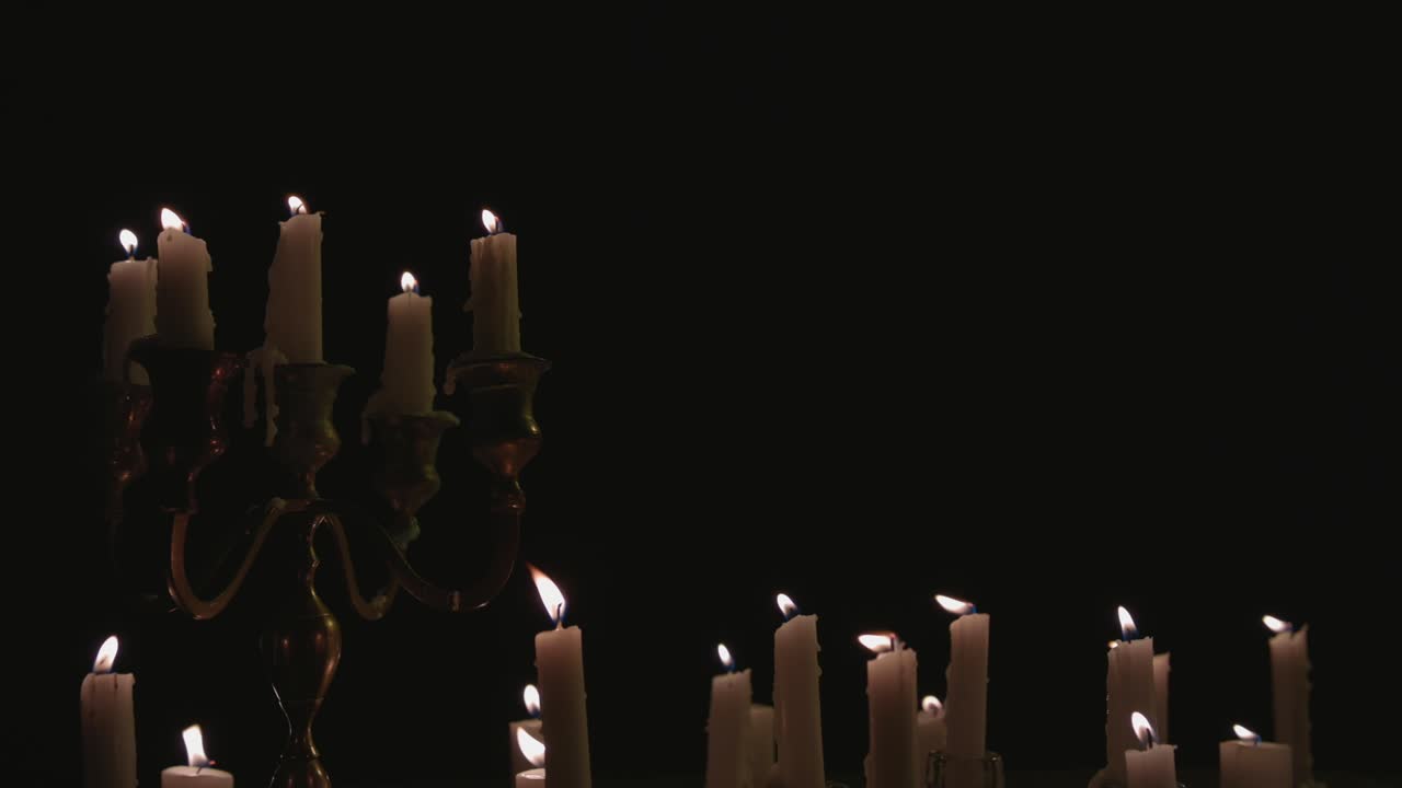 un grupo de velas blancas, algunas en un candelabro, encendidas y funcionando durante un tiempo