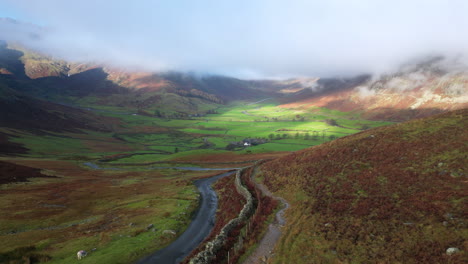 mountain pass road with flight towards sunlit green valley surrounded by mountains