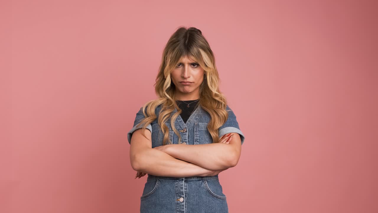 Angry transgender woman nodding head against pink background