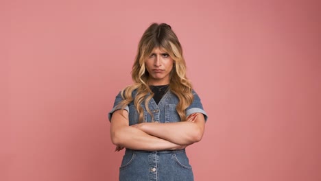 angry transgender woman nodding head against pink background