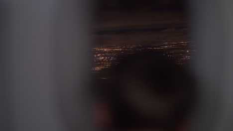 niño mirando la ciudad nocturna desde un avión que se mueve hacia arriba