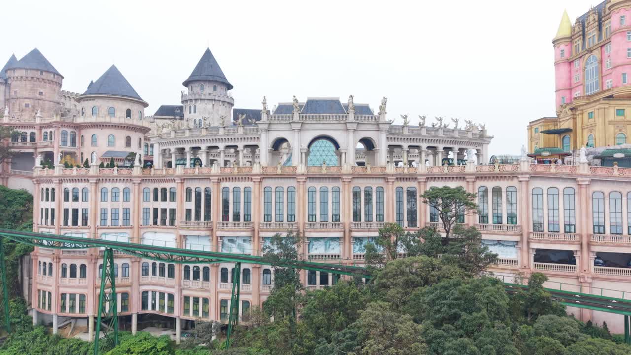 Paisaje elegante de castillo: escena serena de un castillo ornamentado en la ladera, rodeado de abundante vegetación. La suave iluminación nublada realza el ambiente pacífico de este castillo de tonos pastel en una colina brumosa, Ba Na Hills, Vietnam.