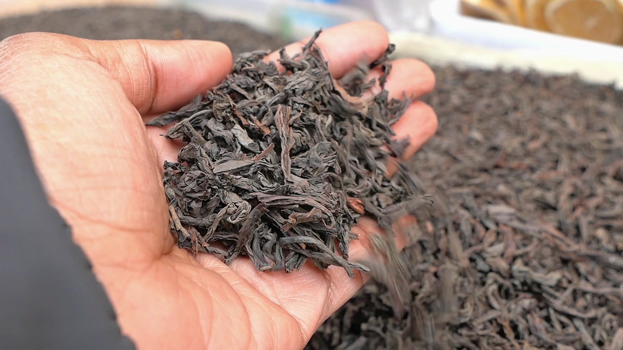 Close-up of Hand Sifting Dried Black Tea Leaves