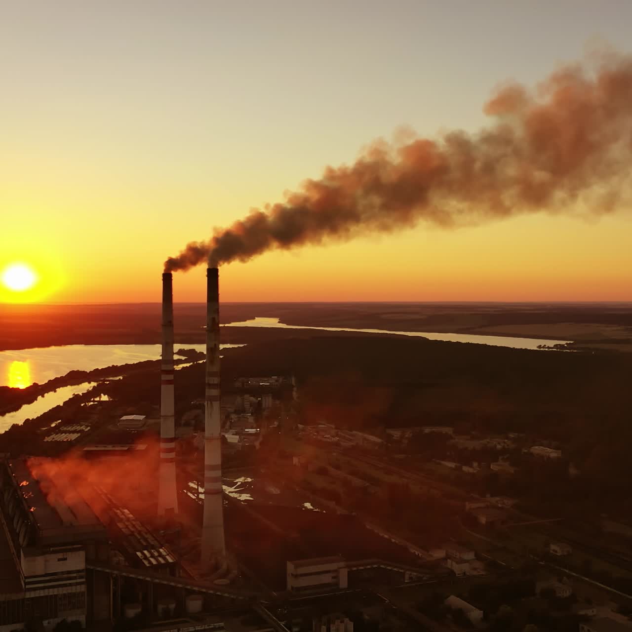 Chemical factory pollute the environment. Harmful smoke released from industrial pipes against the setting sun. Ecological problems.