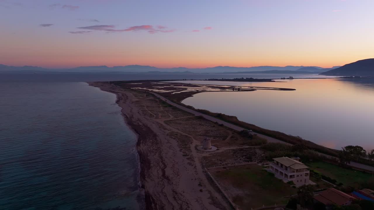 I colori dell'alba si riflettono vicino alle turbine eoliche in cima alla collina in riva al mare, Lefkada, Grecia