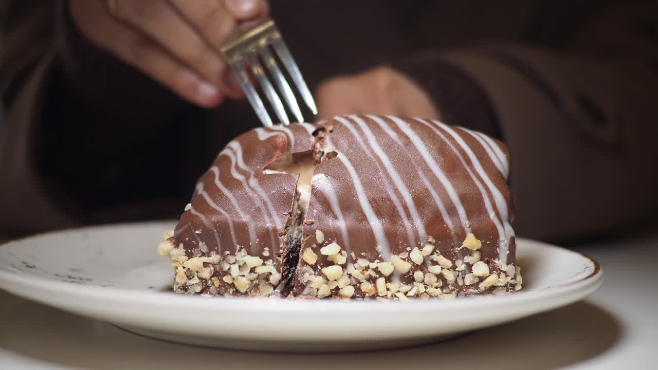Primo piano di mani che tagliano una deliziosa torta al cioccolato