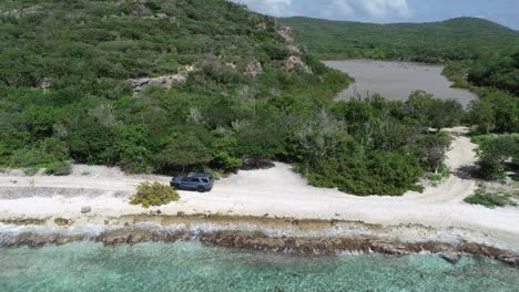 car-driving-offroad-on-rocky-coastline-waves-crashing-drone-view