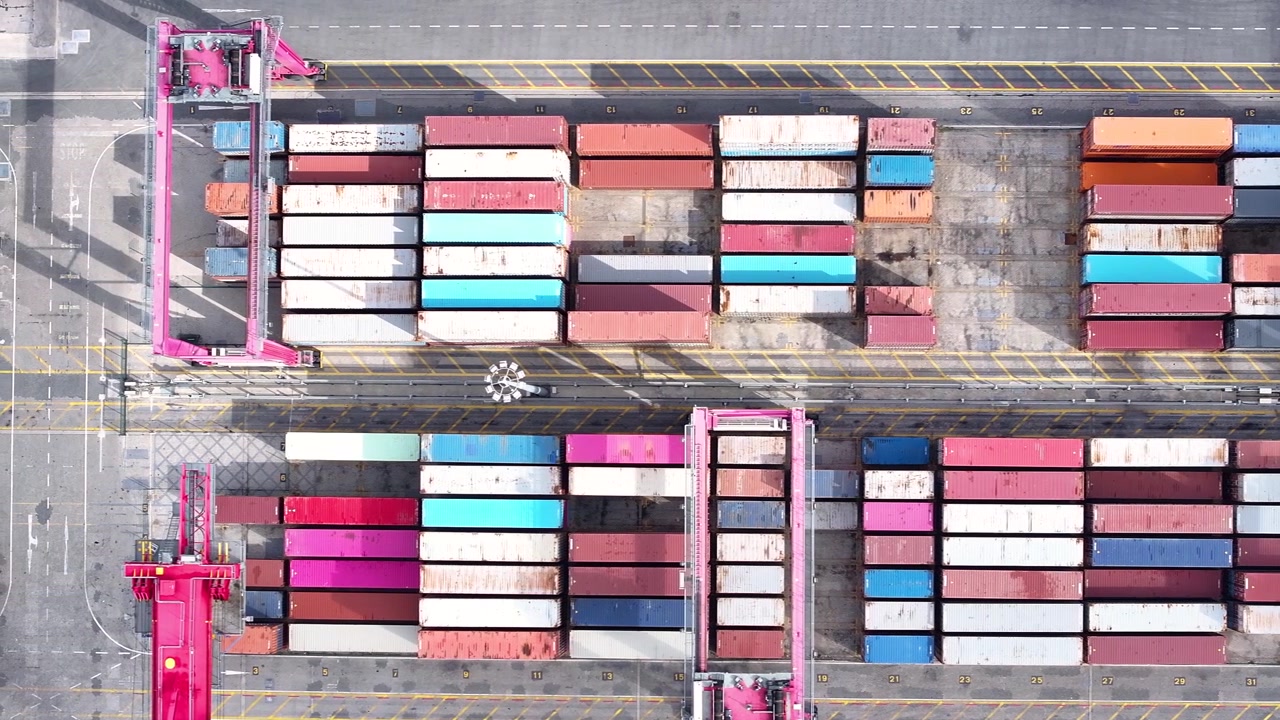I en travl fragthavn er farverige shippingcontainere organiseret i pæne rækker, hvilket fremviser den dynamiske verden inden for maritim logistik.