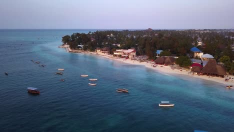 múltiples pequeñas lanchas motoras se sientan ancladas frente a la costa del punto de acceso turístico de la playa de nungwi, zanzíbar, isla en tanzania durante una espectacular puesta de sol