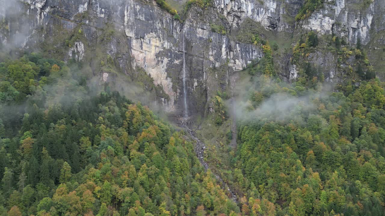 de izquierda a derecha fotografía panorámica de una montaña brumosa con una delgada corriente de cascada que fluye por la colina