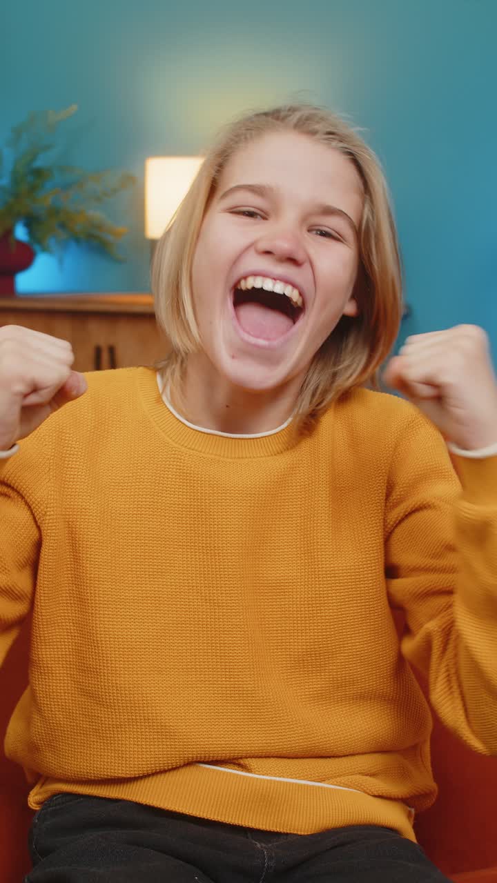 ragazzo adolescente che guarda la tv festeggiando la vittoria applaudendo la squadra sportiva seduto sul divano a casa