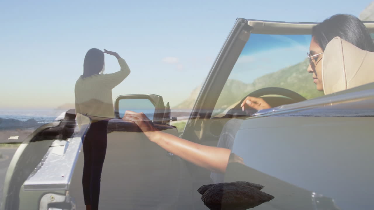 Driving convertible, woman with animation of another woman looking at ocean