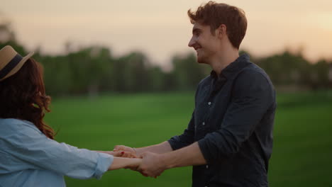 joyful couple turning around on green field in slow motion. loving man and woman