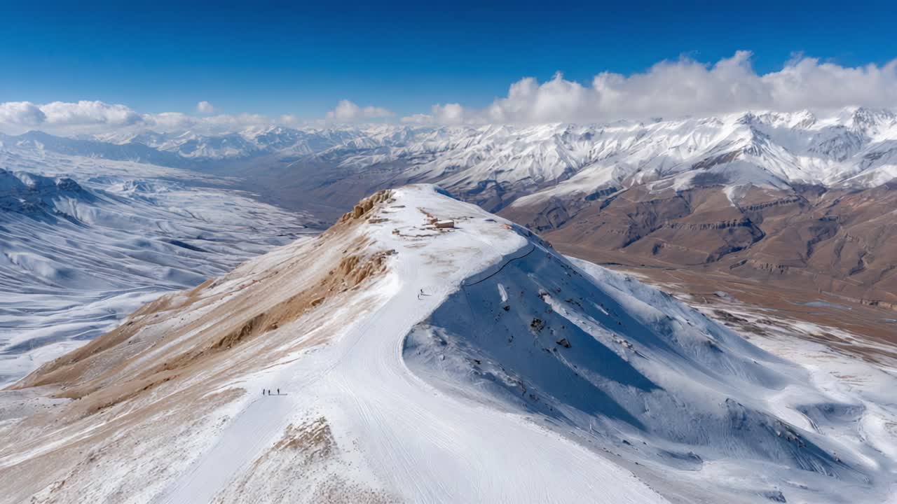 Stunning Aerial View of a Snow-Capped Mountain Peak with Skiers, Showcasing the Majestic Landscape and Natural Beauty of Winter in the Mountains
