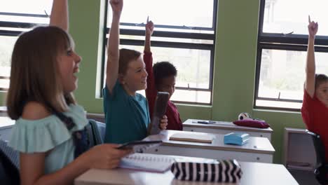 group of kids raising their hands in the class