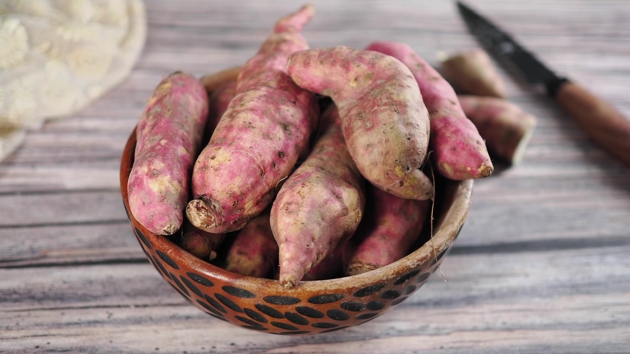 Raw Sweet Potatoes in a Rustic Bowl on Wooden Table