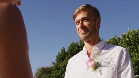 novia y novio caucásicos de pie en el altar al aire libre con el oficiante de la boda durante la ceremonia