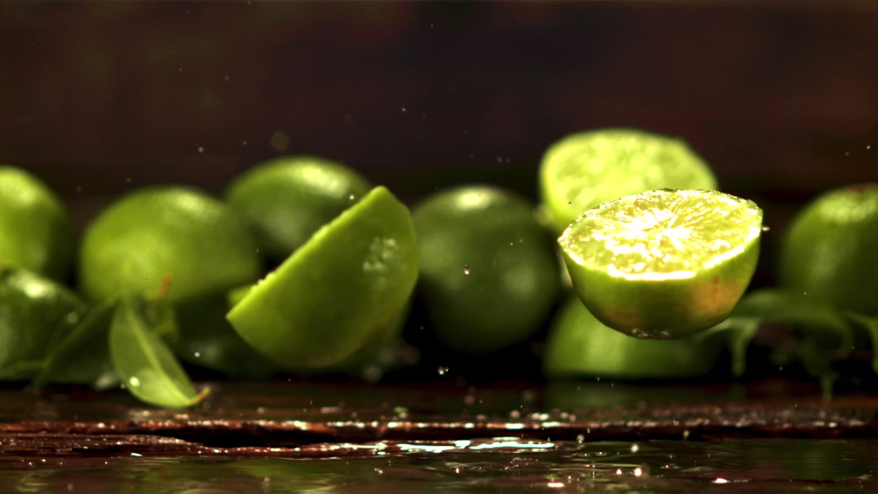 Lime fresco che cade e si spacca al rallentatore con schizzi d'acqua