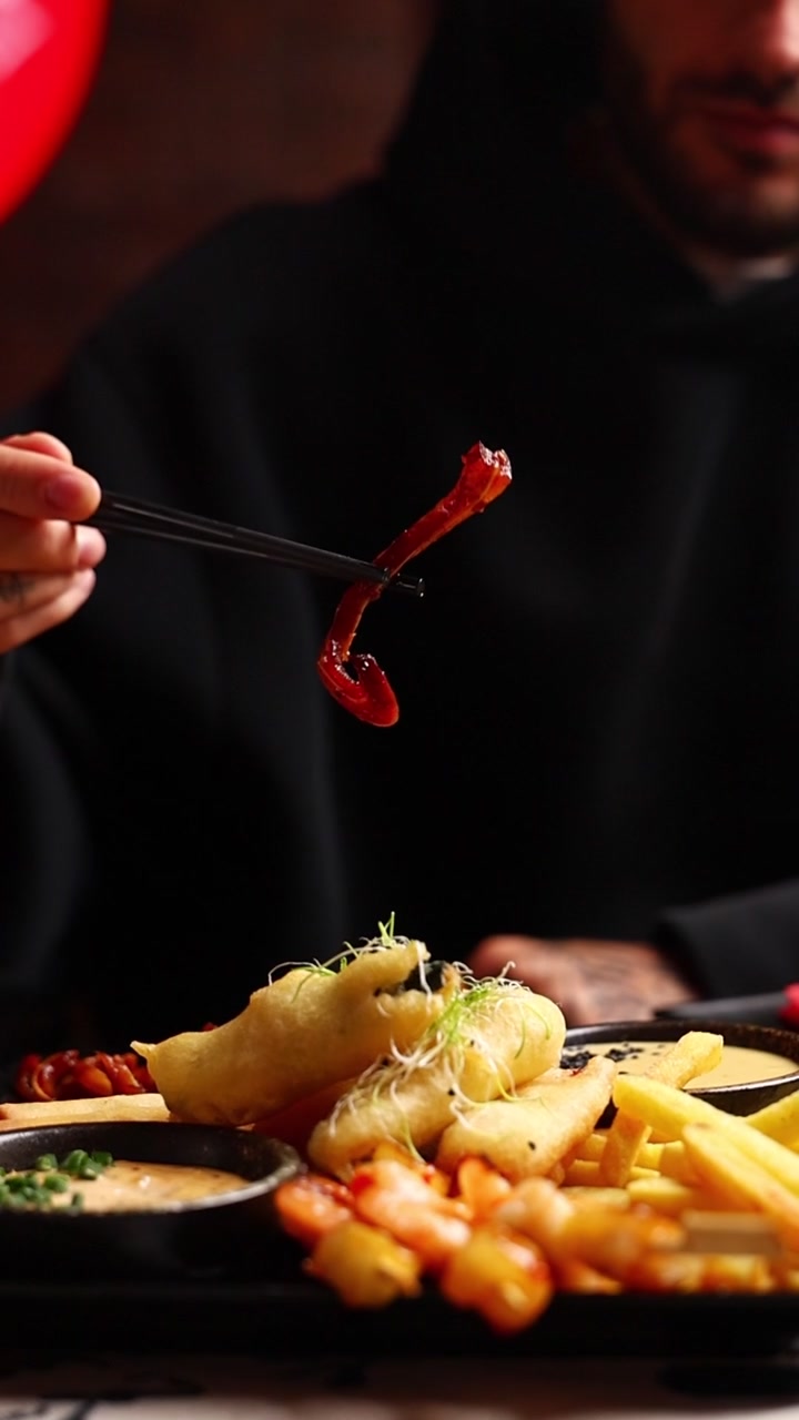 Person Using Chopsticks to Hold Glazed Food Over a Platter
