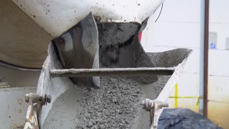 a portable concrete mixer at a construction site with cement falling from a conveyor into a container