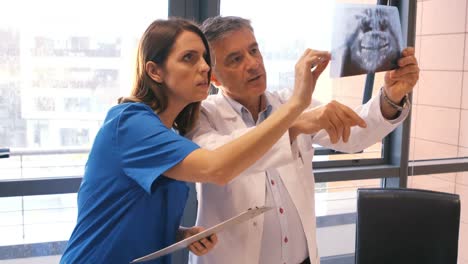 médico examinando rayos x mientras la enfermera escribe en el clipboard