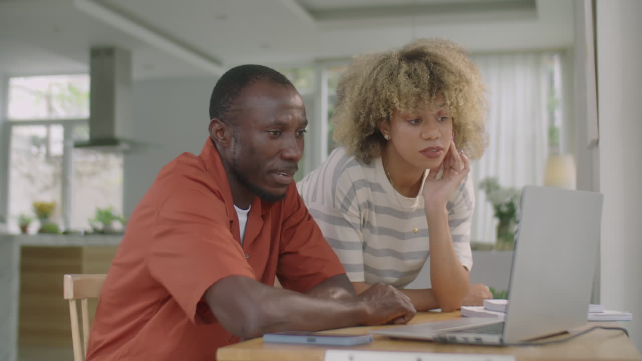 Diverse Couple Using Laptop and Talking at Home