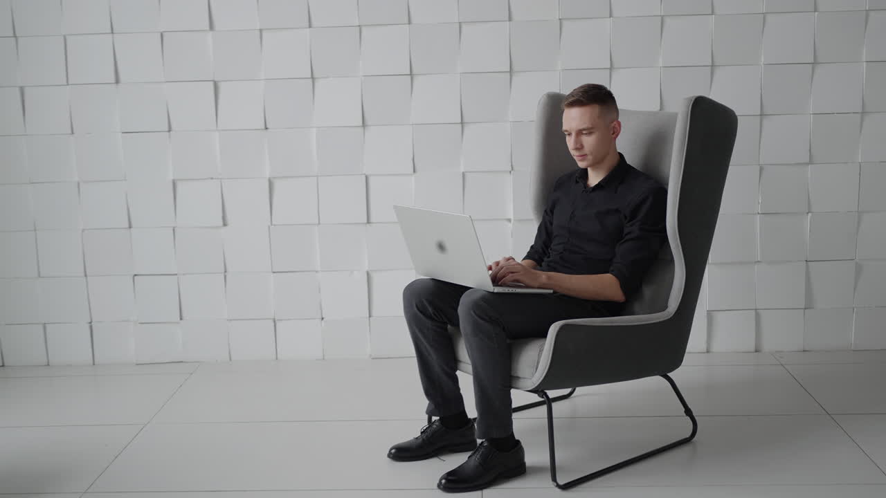 현대 의자 에서 노트북 을 사용 하는 사람