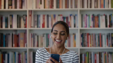 portrait cute young indian woman using smartphone enjoying watching online entertainement laughing listening to music wearing earphones slow motion