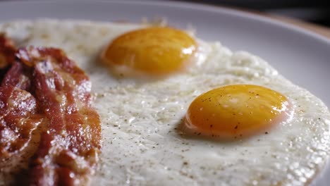 cooked eggs and bacon in a plate ready to eat