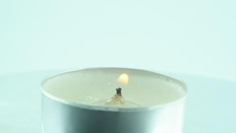 A-rotating-shot-of-a-lighting-small-white-candle,-360-4K