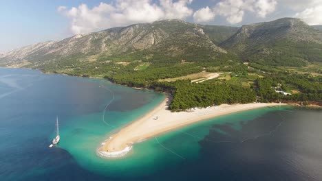 an aerial view shows zlatni rat beach and its surrounding mountains on brac island croatia