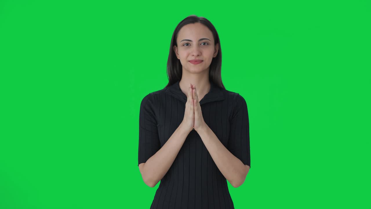 Happy Indian female news anchor doing Namaste Green screen