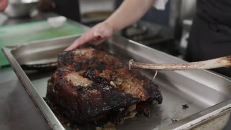 caucasian male chef taking out bones from roasted meat in kitchen, slow motion