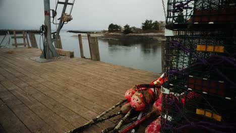 Lobster-traps-and-fishing-bouys-with-crane-lift-in-Maine-tilting-wide-shot,-4k