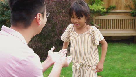 excited asian daughter runs across garden to show father feather she has found - shot in slow motion